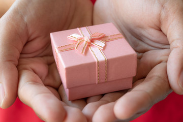 Close up human hand holding small gift box for valentine and other holiday event