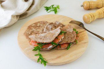 Rye cakes with salmon, arugula and goat cheese on a wooden board. Healthy food, gluten free.