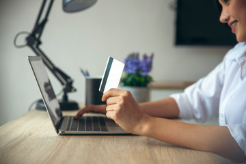 Asian woman holding credit cart and using laptop to shopping online.Shopaholic girl selecting products to cart in online website And pay via internet banking.