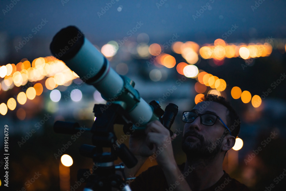 Canvas Prints astronomer with a telescope watching at the stars and moon with blurred city lights in the backgroun