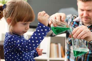 Man and little girl play with colourful liquids portrait. Young team clean research equipment...