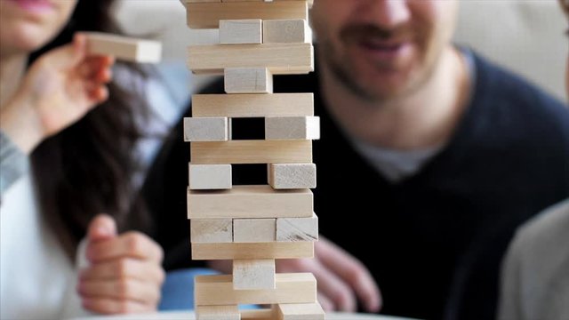Close-up of wooden tower is crumbling while family playing game together in slow motion