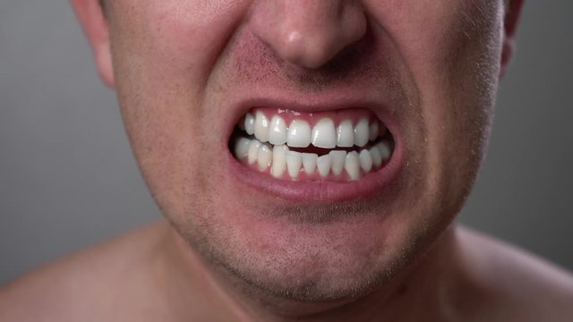 Man with angry facial expression is screaming out loud. Portrait of a shouting man with mouth wide open. Furious yelling man. Anger emotions. Anger. Violence. Mouth and grin close-up. White teeth.