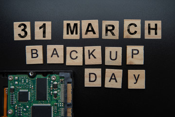 Words in English Backup day. Copy space for text. HDD hard drive. hard disk on black dark background with selective focus and crop fragment.