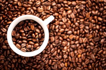 White cup with coffee beans on a background of coffee beans