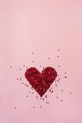 Valentine's Day concept. Heart symbol made of sparkles confetti on pink background. Flat lay, top view minimal holiday composition.