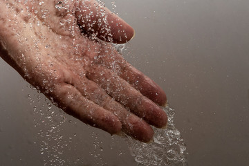 Fototapeta premium Falling water drops and human hand.