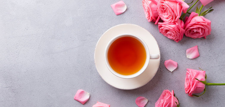 Cup of tea with pink rose. Grey stone background. Top view. Copy space.