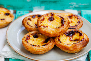 Egg tart, traditional Portuguese dessert, pastel de nata on a plate. Colorful wooden background. Close up.