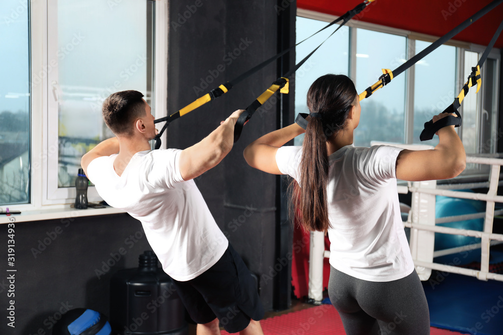 Poster Couple working out with TRX system in gym