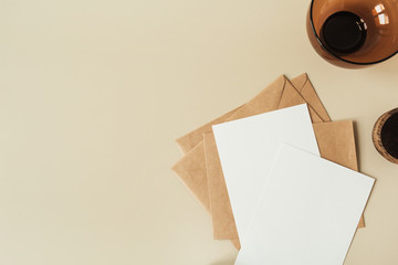 Blank paper sheets with empty copy space for text, envelopes on beige background. Flat lay, top view mail letter invitation.
