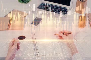 Hands writing information about stock market in notepad. Forex chart holograms in front. Concept of research. Multi exposure