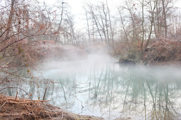 misty pond with fog in the countryside at winter time