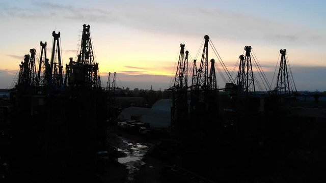 Silhouette of abandoned construction cranes, industrial area at sunset. Cemetery of cranes in Minsk