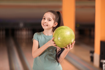 Fototapeta premium Little girl with ball in bowling club