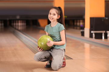 Fototapeta premium Little girl with ball in bowling club