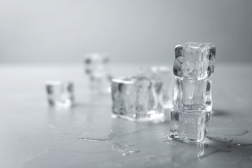 Crystal clear ice cubes with water drops on grey table. Space for text