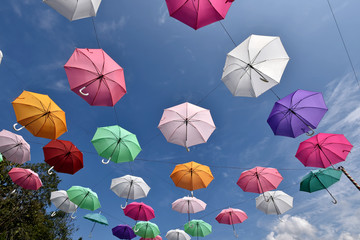 Fototapeta na wymiar Colorful umbrellas are hanging from wire with blue sky cloud in background