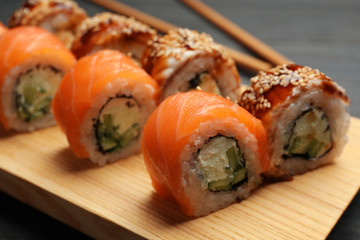 Delicious sushi rolls on wooden tray, closeup