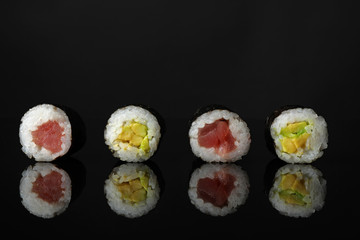 Delicious sushi rolls on black mirror surface