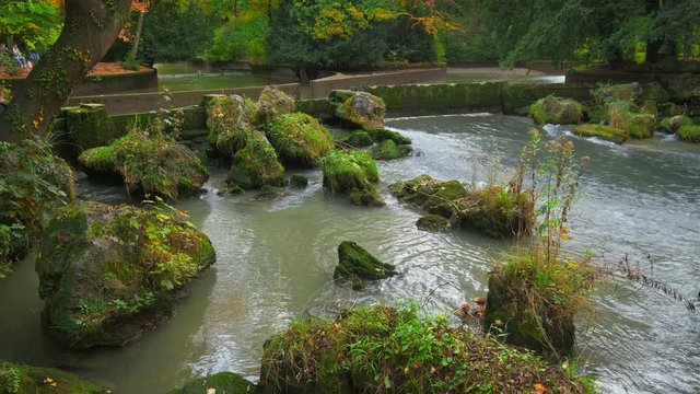 Munich English garden Englischer garten park. Autumn colours on trees and leaves and flowing river. Munchen, Bavaria, Germany