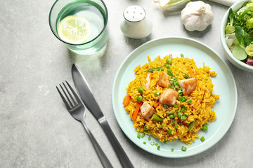 Delicious rice pilaf with vegetables and chicken served on light grey table, flat lay
