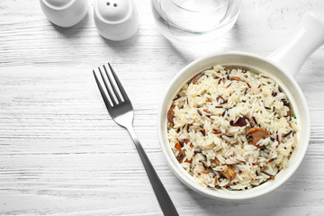 Delicious rice pilaf with mushrooms on white wooden table, flat lay