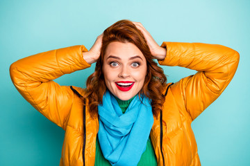 Closeup photo of beautiful funny lady red lips open mouth shopping season hands on head wear yellow overcoat blue scarf green turtleneck isolated teal color background