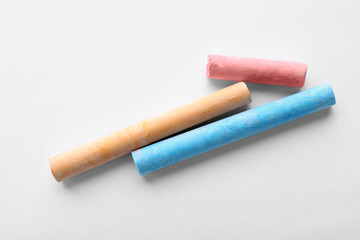 Color pieces of chalk on white background, top view
