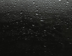 Rain drops on glass against black background