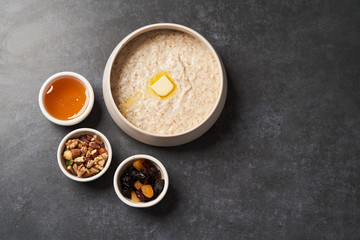 Obraz na płótnie Canvas Oatmeal porridge with raisins, honey and nuts in a bowl