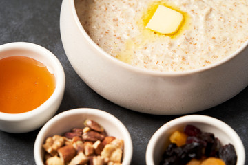 Oatmeal porridge with raisins, honey and nuts in a bowl