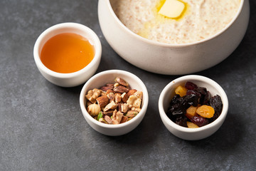 Oatmeal porridge with raisins, honey and nuts in a bowl