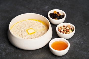 Oatmeal porridge with raisins, honey and nuts in a bowl