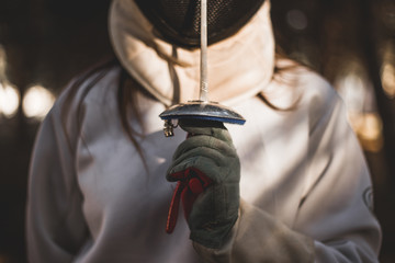 Detalle de mano y espada de esgrimidor en luces y sombras
