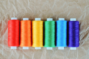LGBT flag colors creative concept. Rainbow color sewing treads on the craft paper background.