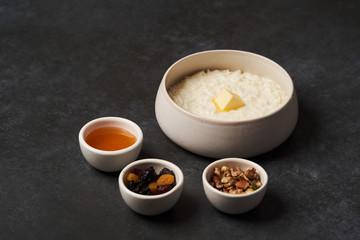 Rice porridge with milk, raisins, honey and nuts in a bowl.