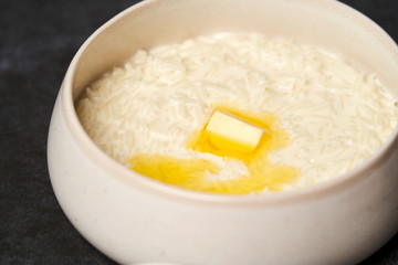 Rice porridge with milk, raisins, honey and nuts in a bowl.