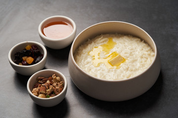 Rice porridge with milk, raisins, honey and nuts in a bowl.