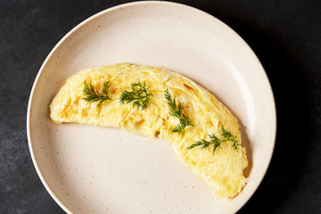 Traditional breakfast omelettes on a white plate on dark background