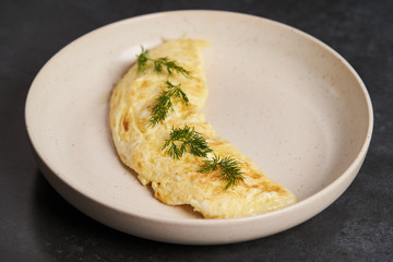 Traditional breakfast omelettes on a white plate on dark background