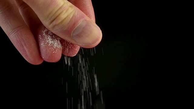 male hand salt food on black background