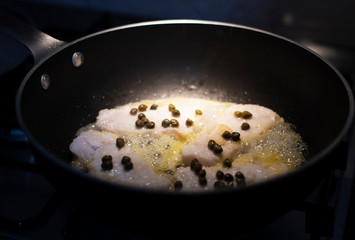 Fish fillets sizzling in hot oil and wine