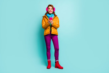 Full length photo of pretty lady hold telephone writing new post blog wear trendy casual yellow overcoat scarf purple trousers shoes isolated teal color background
