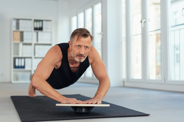 Middle-aged man exercising plank on balance board