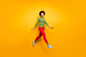 Fototapeta na wymiar Full length body size turned photo of curly wavy brunette hair girl running jumping in red trousers white footwear isolated vivid color background