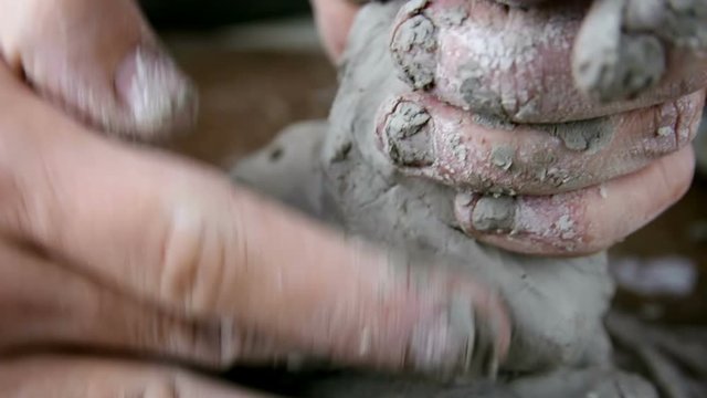 Sculptor man creating sculpture from clay in workshop. Process of making a clay figure.
