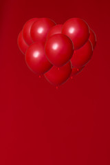red helium balloons on red background in a shape of heart