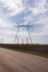 Rural landscape. Electric power lines in the field on blue sky background