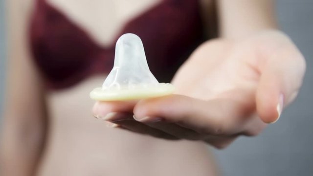 Girl in a bra gives a condom into the camera.Attractive, naked, girl, in a bra.